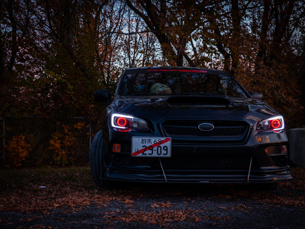 Subaru WRX with demon head lights and orange leaves in the background